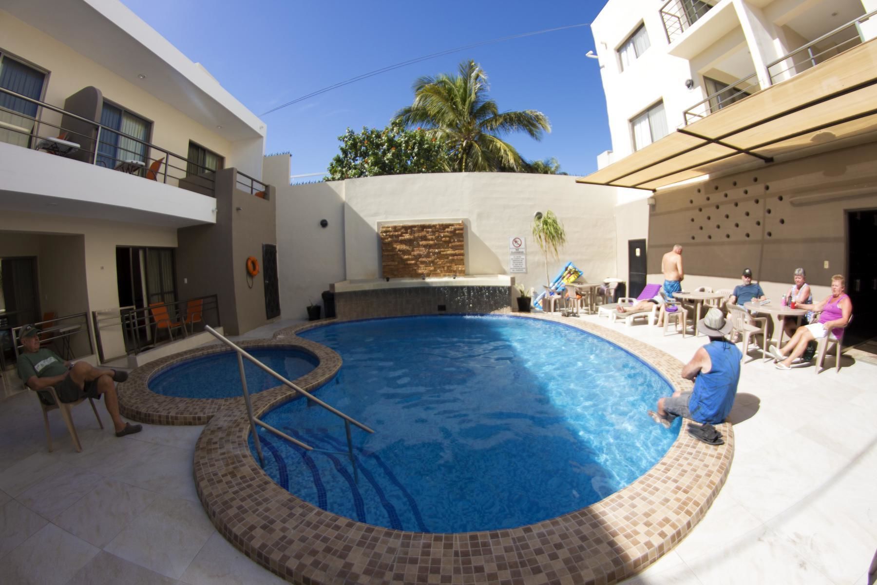 A swimming pool with a tiled edge, surrounded by lounge chairs and tables.