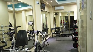 A gym with cardio machines, weight benches, and dumbbells. - Hotel & Suites Domani (Progreso)