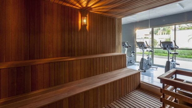 Un espace sauna avec des bancs en bois et une vue sur les appareils de musculation en plein air.