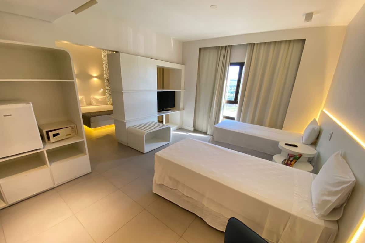 Habitació d'hotel moderna amb llit, zona de seients, televisió i minibar.