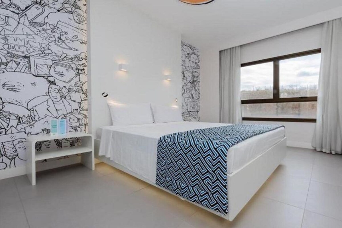 Una habitación de hotel moderna con una cama grande, un escritorio y una ventana con cortinas.