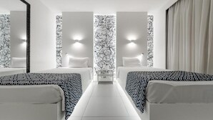 A hotel room with two beds, a central seating area, and patterned wallpaper. - Golden Tower Shopping by Fênix Hotéis (Pouso Alegre)