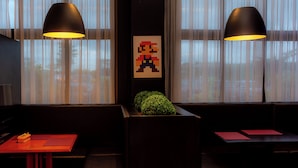 A room with two black pendant lamps, a pixel art of a character on the wall, and a plant in a planter. - Golden Tower Shopping by Fênix Hotéis (Pouso Alegre)