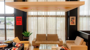 A modern hotel lobby with a sofa, a coffee table, and a dining area with plates and utensils. - Golden Tower Shopping by Fênix Hotéis (Pouso Alegre)