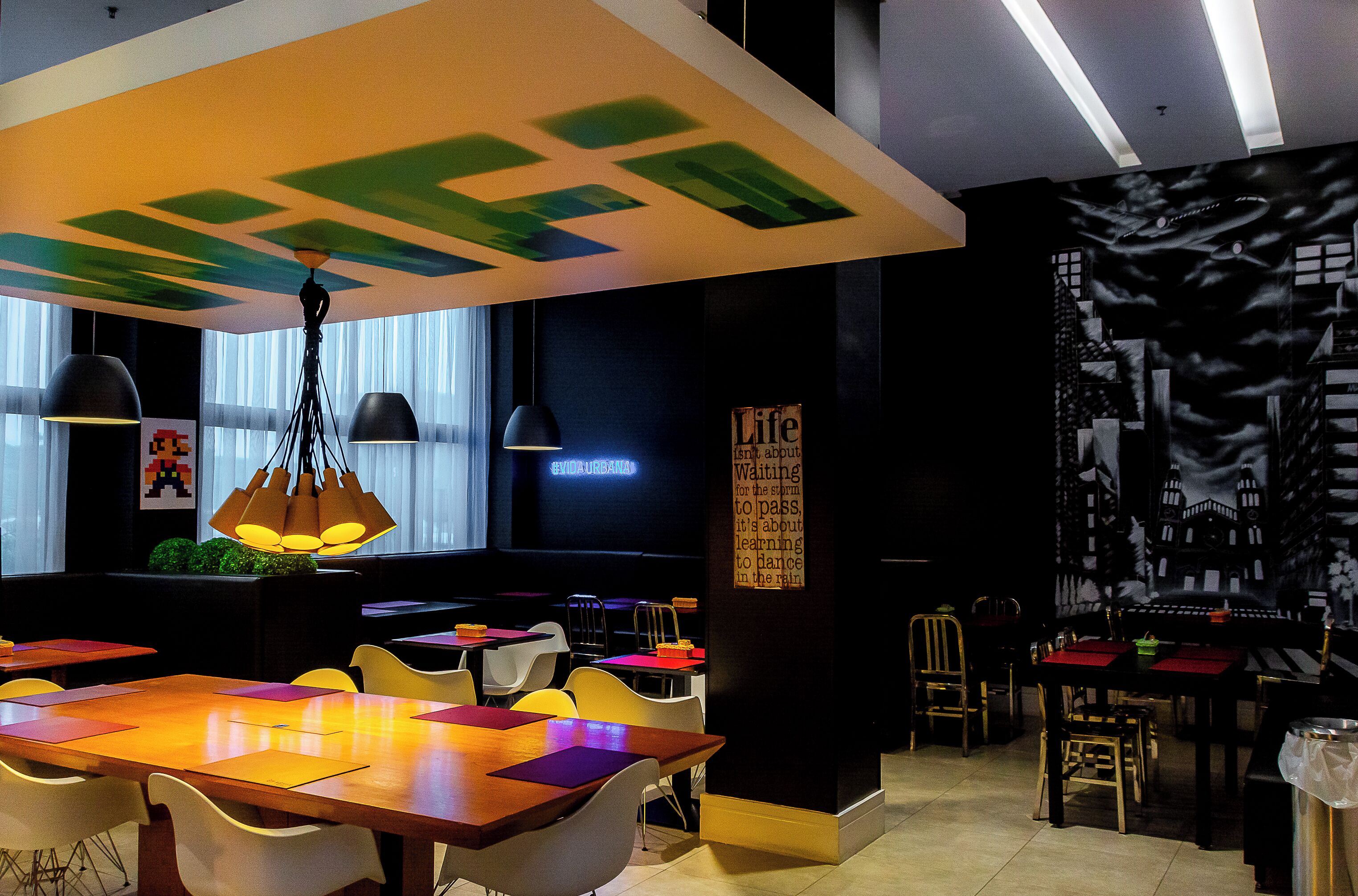 A modern restaurant with a variety of seating options, including tables and chairs, and a large mural on the wall.