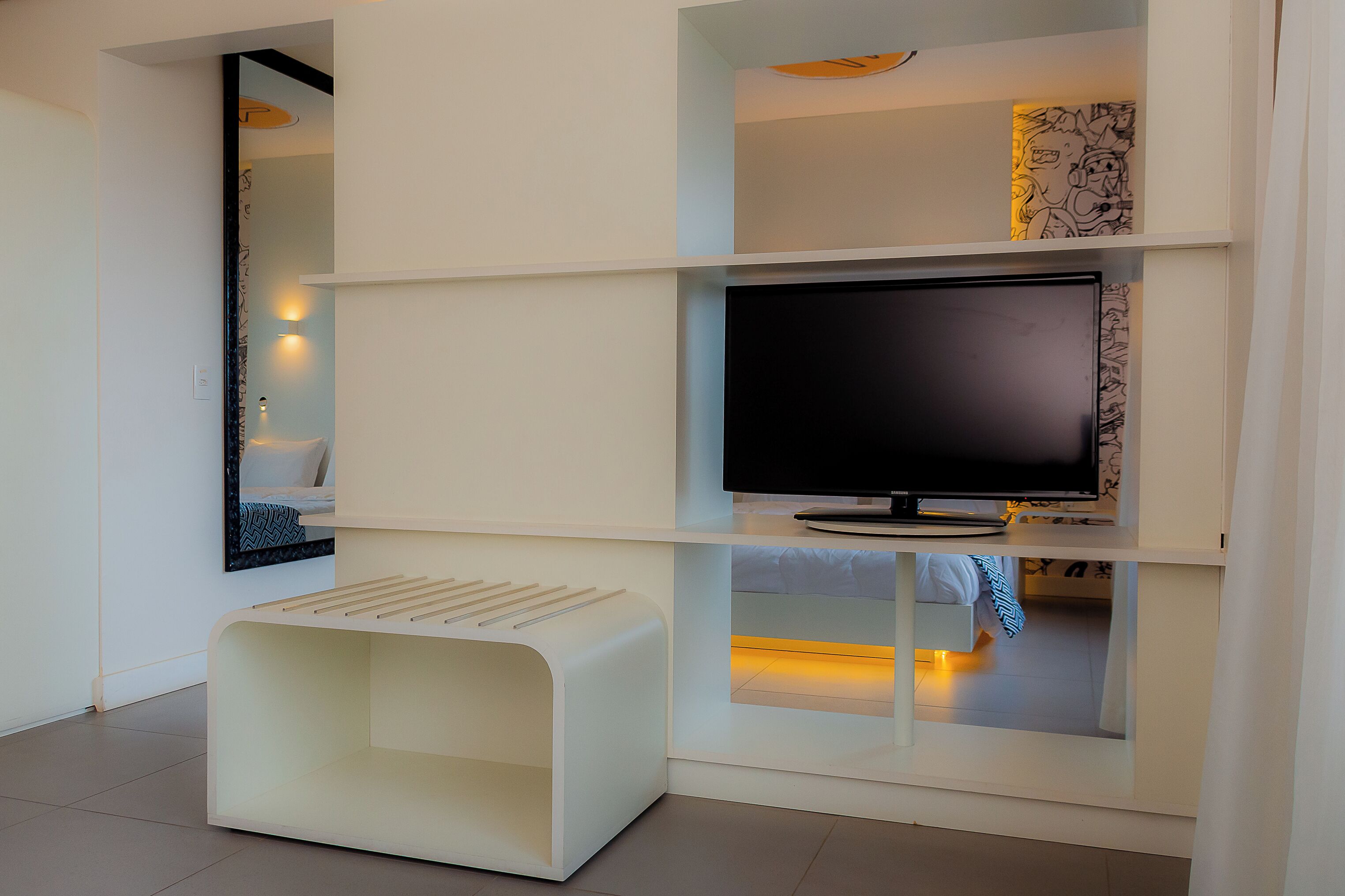 Una sala de estar moderna con un televisor de pantalla plana, un mueble blanco para entretenimiento y un banco empotrado.