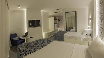 Een hotelkamer met twee bedden, een bureau met een laptop, een stoel, een kledingkast en een spiegel.