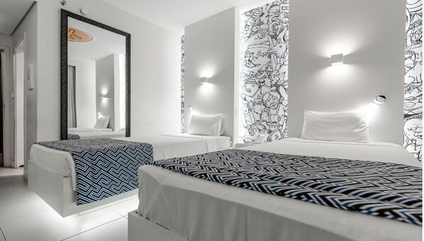 Une chambre d’hôtel avec deux lits, un grand miroir et un papier peint à motifs.
