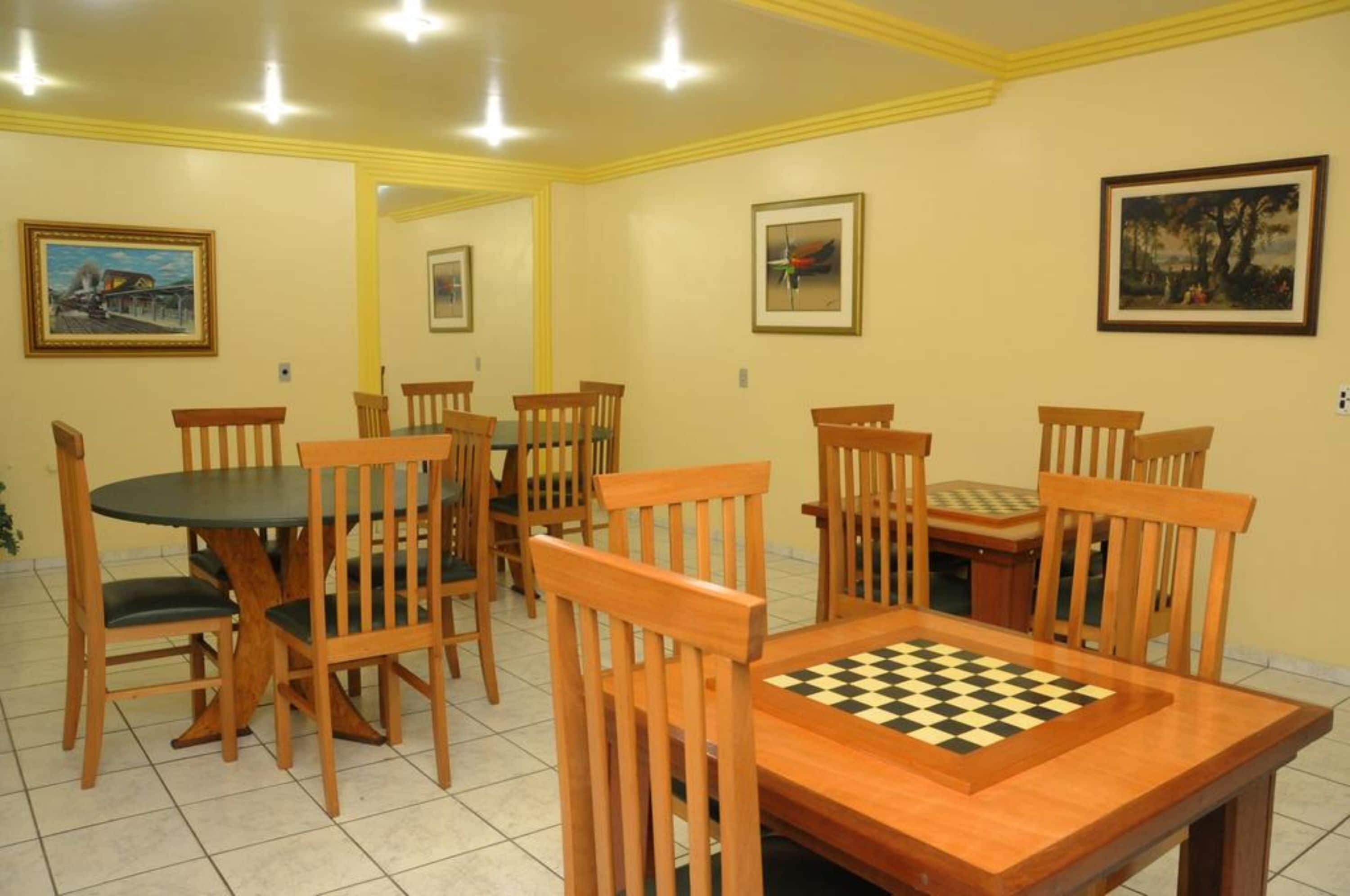 Un coin repas avec des chaises et une table en bois, agrémenté d’un jeu d’échecs.