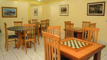 A dining area with wooden chairs and a table, featuring a chessboard.