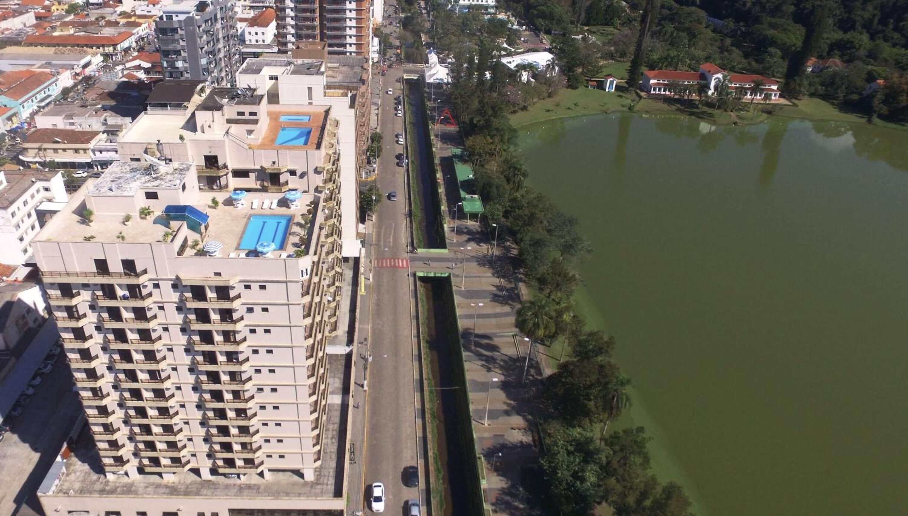 Un immeuble de grande hauteur doté de nombreux balcons, d’une piscine et situé à proximité d’une voie d’accès menant à un plan d’eau.