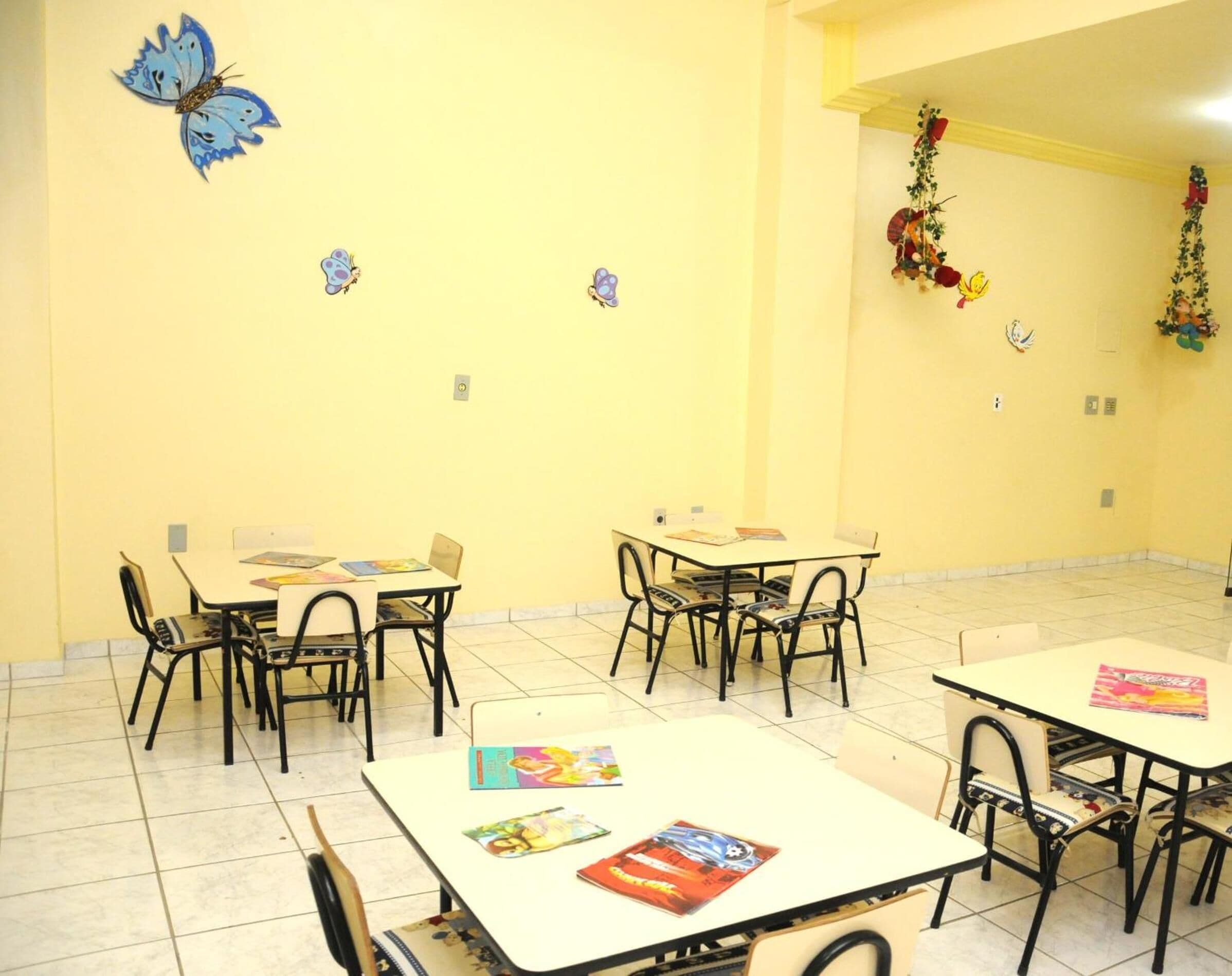 A classroom with tables and chairs, educational posters, and butterfly decorations on the wall.