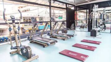 Et fitnesscenter med løbebånd, styrkemaskiner og træningsmåtter.