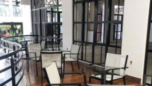 An indoor seating area with wooden flooring and metal-framed chairs. - Hotel Metropole (Sao Lourenco)