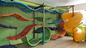 A play area with multiple slides and swings, enclosed by a netted fence. - Hotel Metropole (Sao Lourenco)