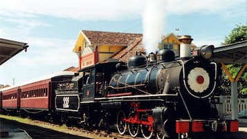 A steam locomotive with the number 332 on the front, parked at a station with a yellow building in the background.