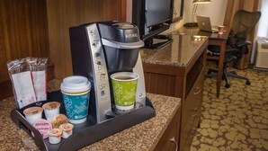 A coffee station with a Keurig machine, disposable cups, and food items like yogurt and granola. - Hilton Garden Inn Jackson/Flowood (Flowood)