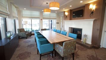 A conference room with a long table, blue chairs, a fireplace, and a TV mounted on the wall.