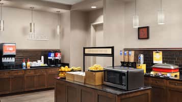 A breakfast bar with coffee machines, a microwave, and various food items.