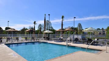 Relax by the pool surrounded by lounge chairs and umbrellas.