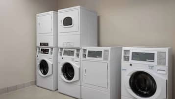 A row of stacked, modern, white laundry machines in a clean, tiled room.