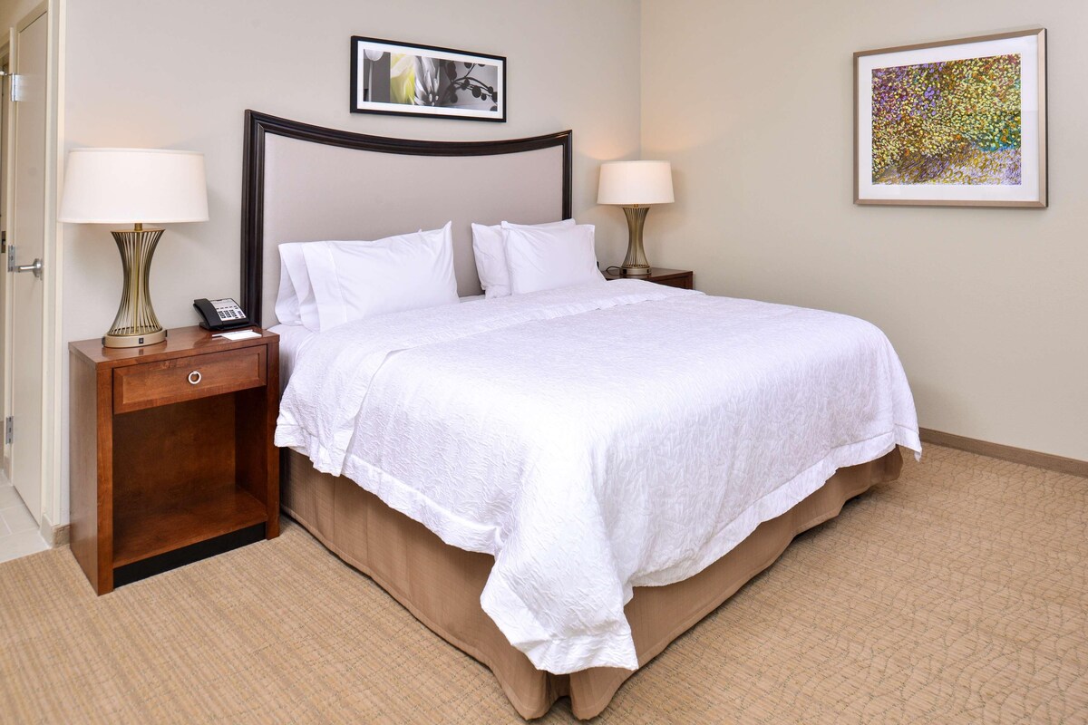 A neatly made bed with white linens, a wooden headboard, and two bedside tables with lamps.