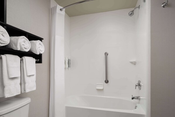 A modern bathroom with a bathtub, a toilet, and a shelf with neatly folded towels. - Hampton Inn & Suites Orlando/Downtown South - Medical Center (Orlando)