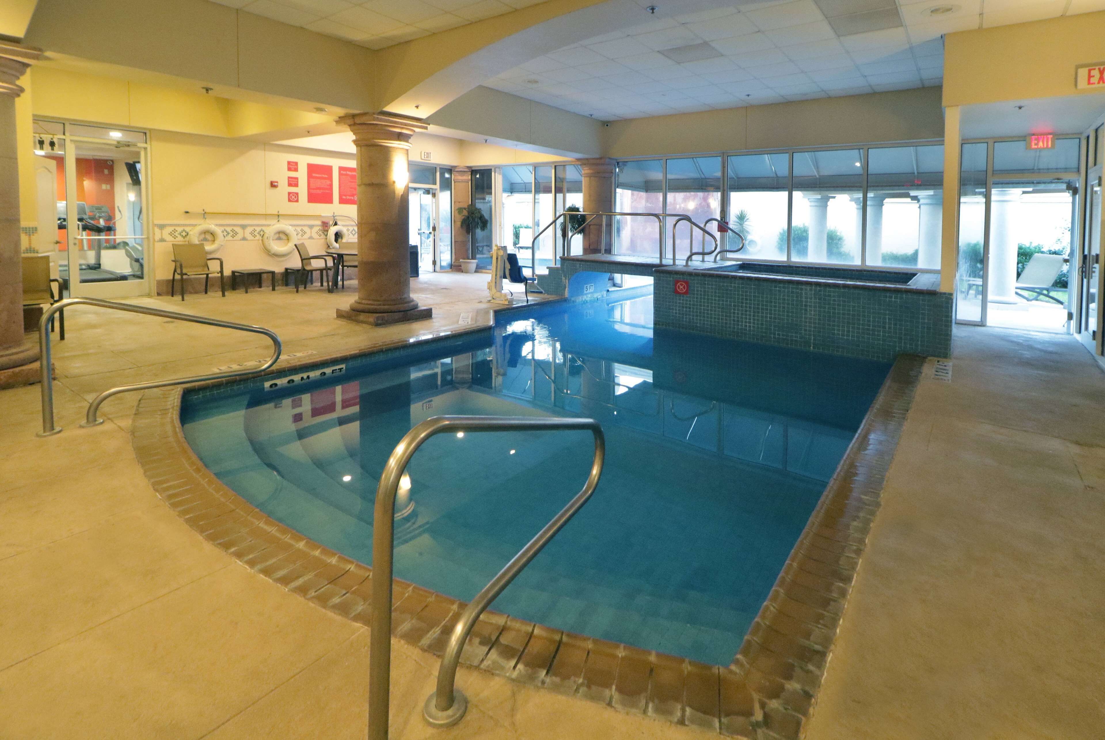 An indoor swimming pool with a tiled edge, a lifeguard chair, and a clear view of the pool area.