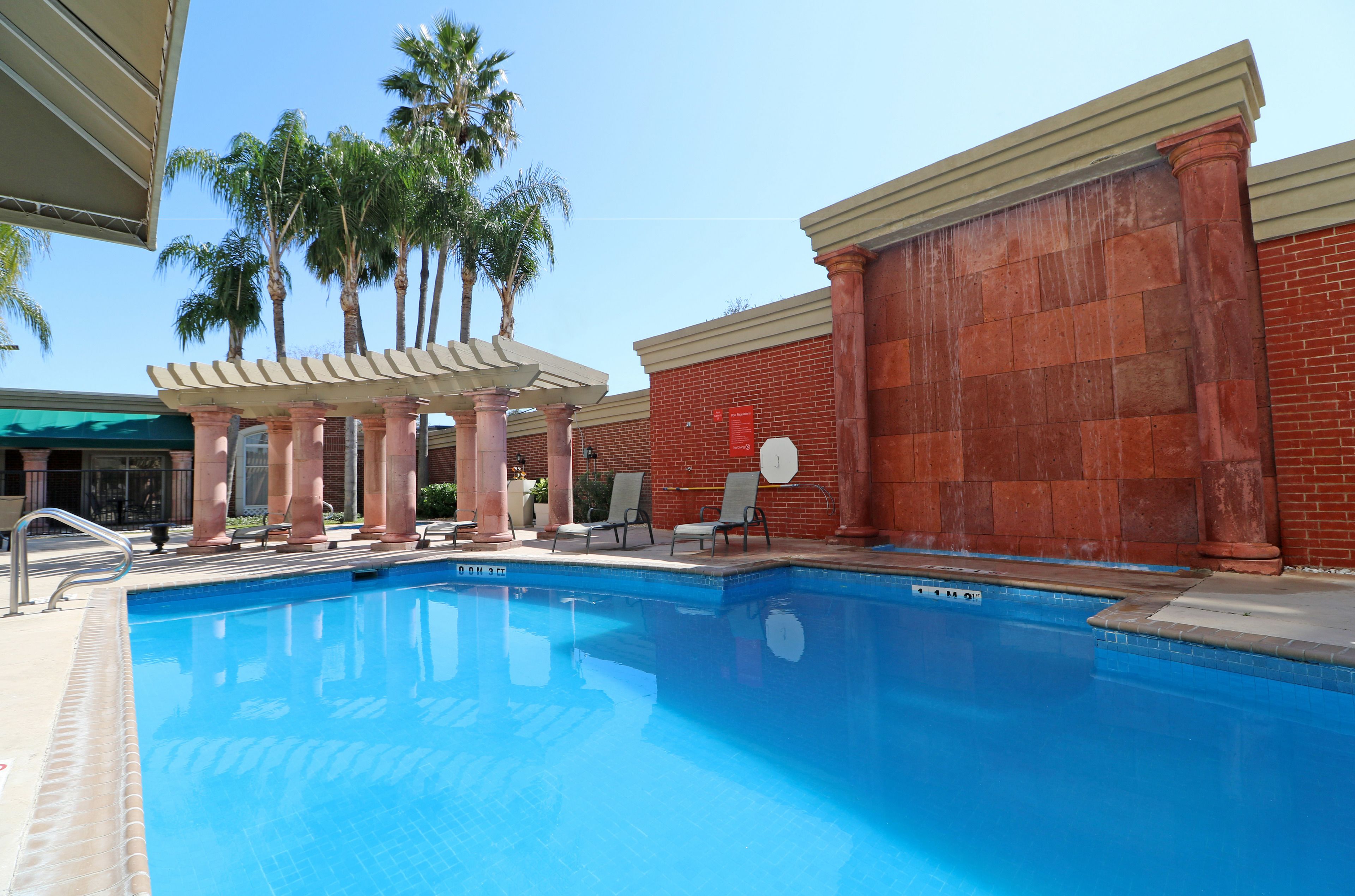 A swimming pool with lounge chairs and palm trees.