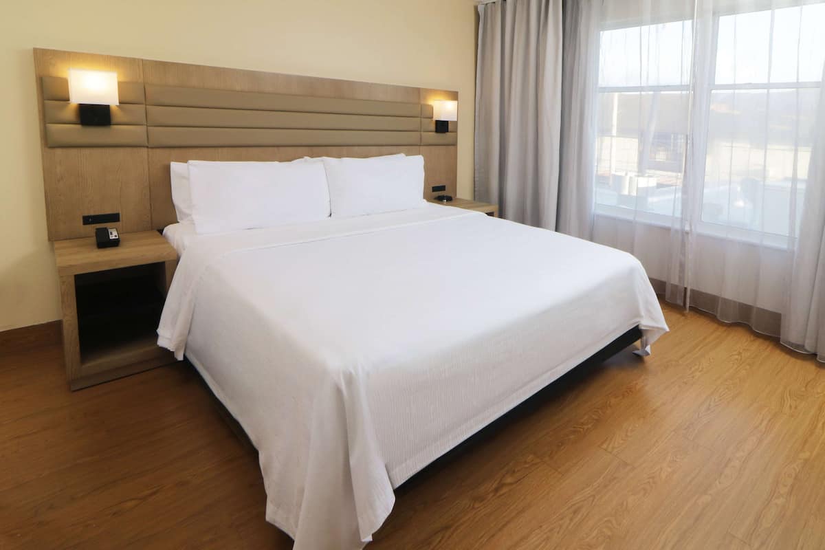 A neatly made bed with white linens in a hotel room.