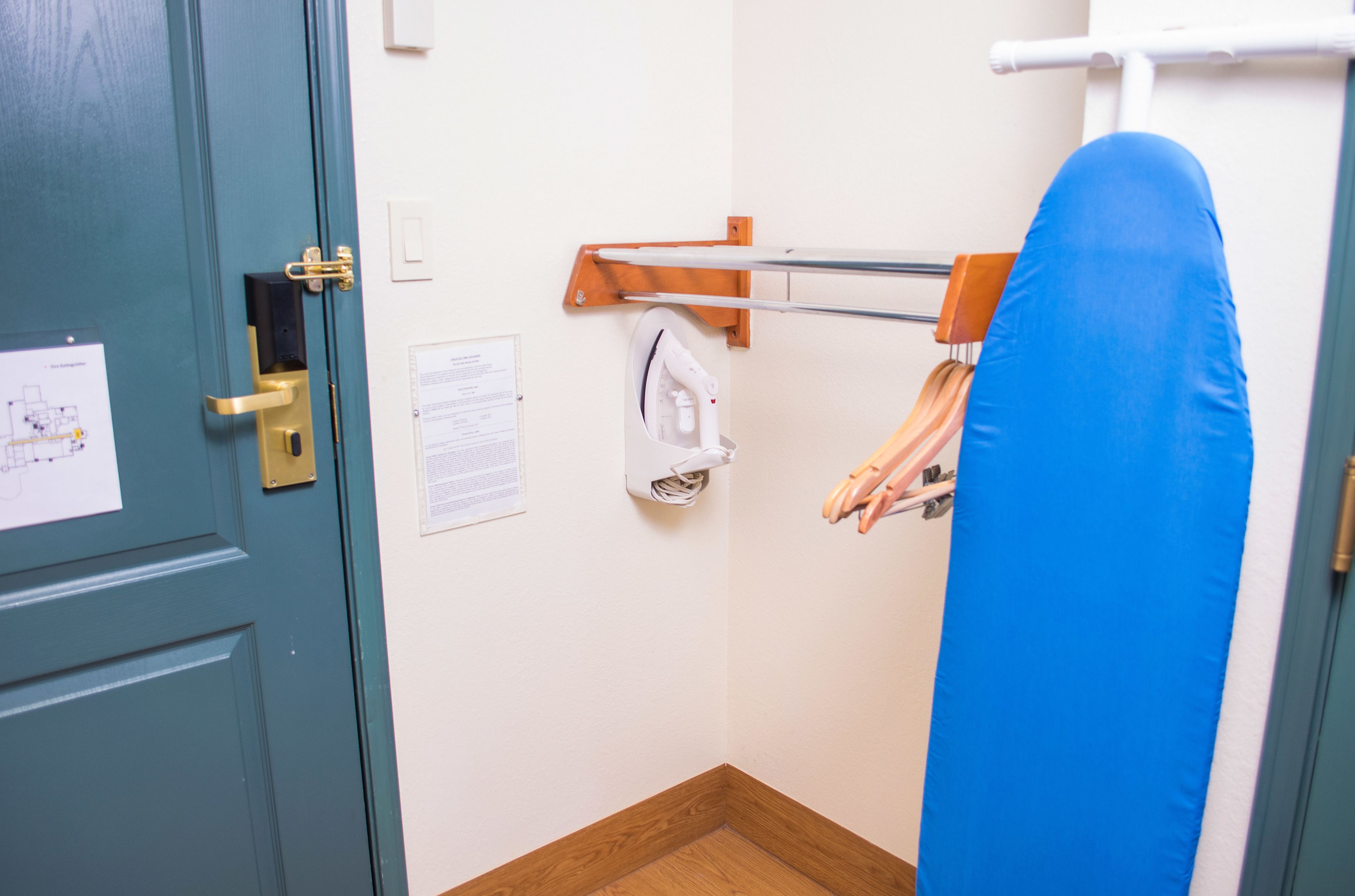 Une pièce avec une porte bleue, une planche à repasser fixée au mur et un tapis de sport bleu.