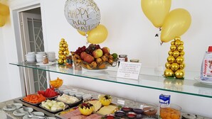 Een buffet met diverse gerechten en gouden ballonnen.