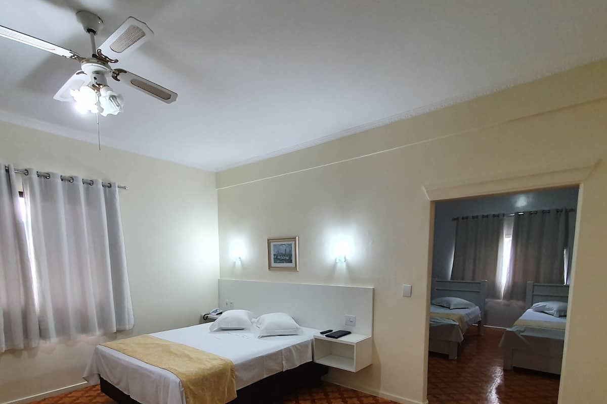 A hotel room with a bed, bedside table, and a ceiling fan.