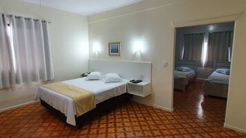 Quarto de hotel com cama, mesa de cabeceira e ventoinha no teto.