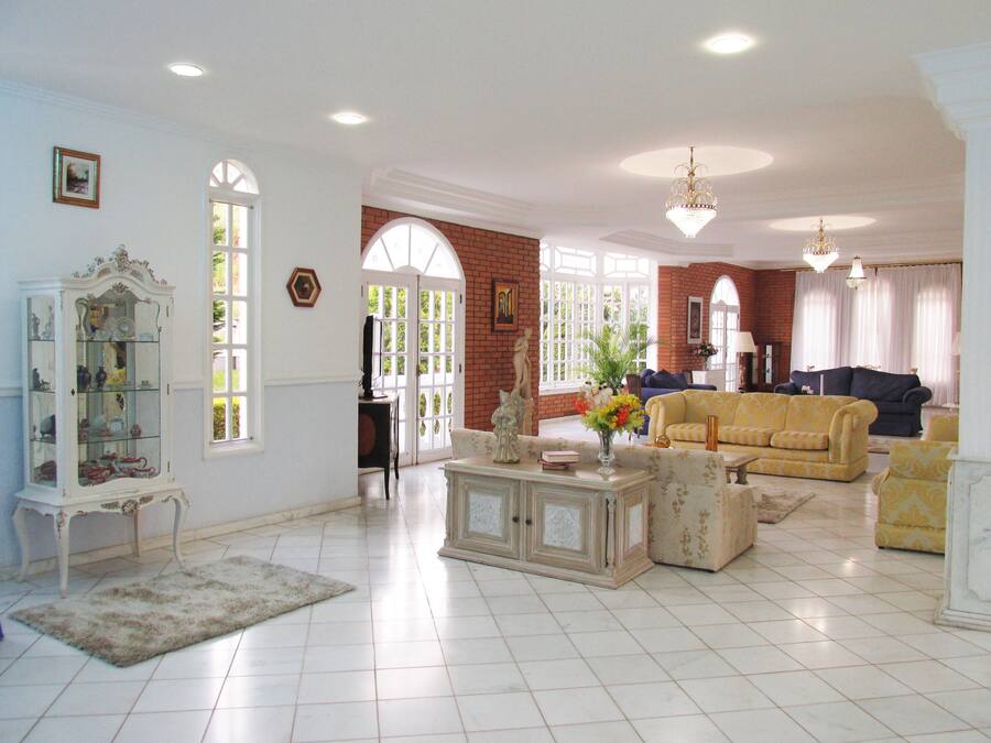 A spacious living room with a large window, a fireplace, and a chandelier.