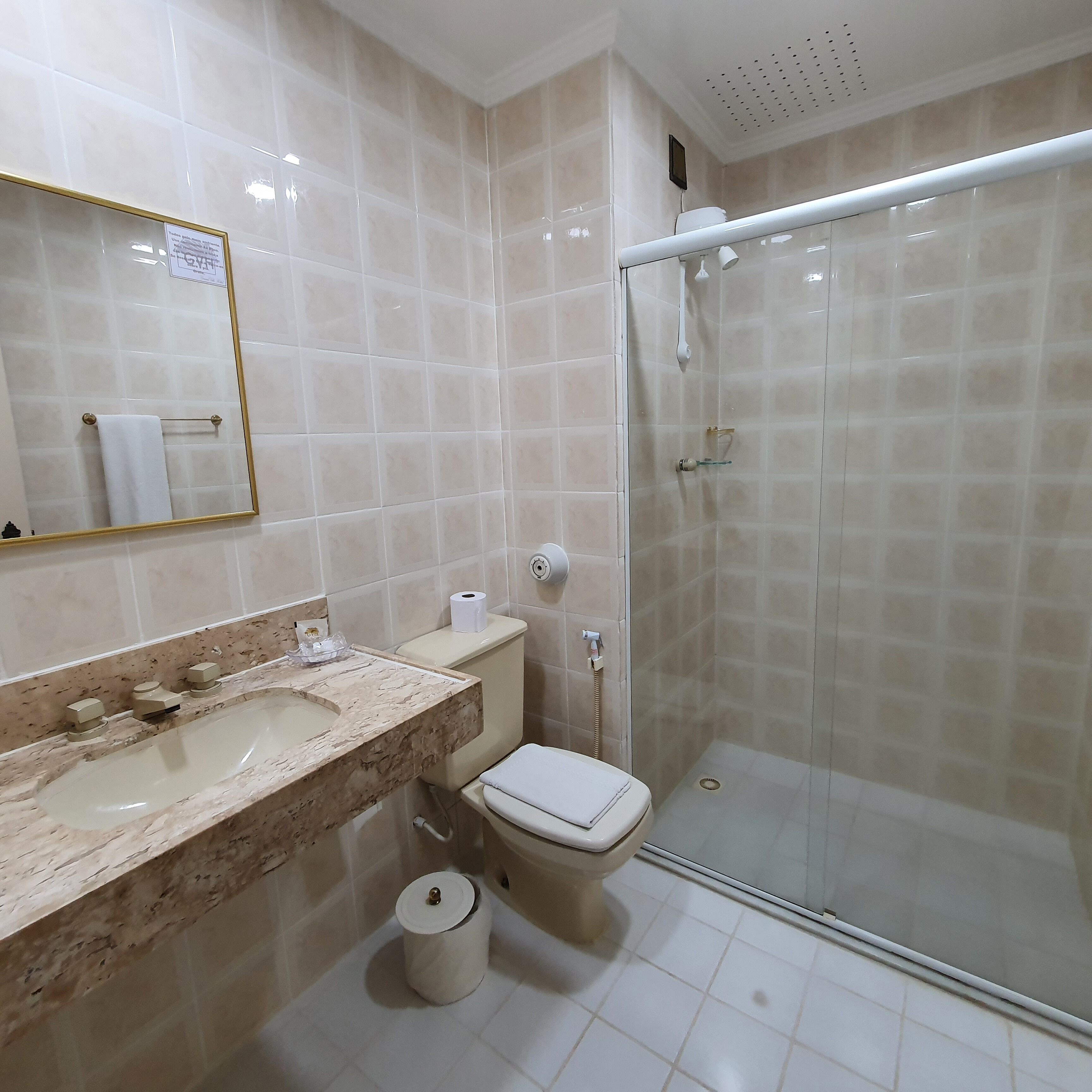 A bathroom with a marble sink, toilet, and glass-enclosed shower.