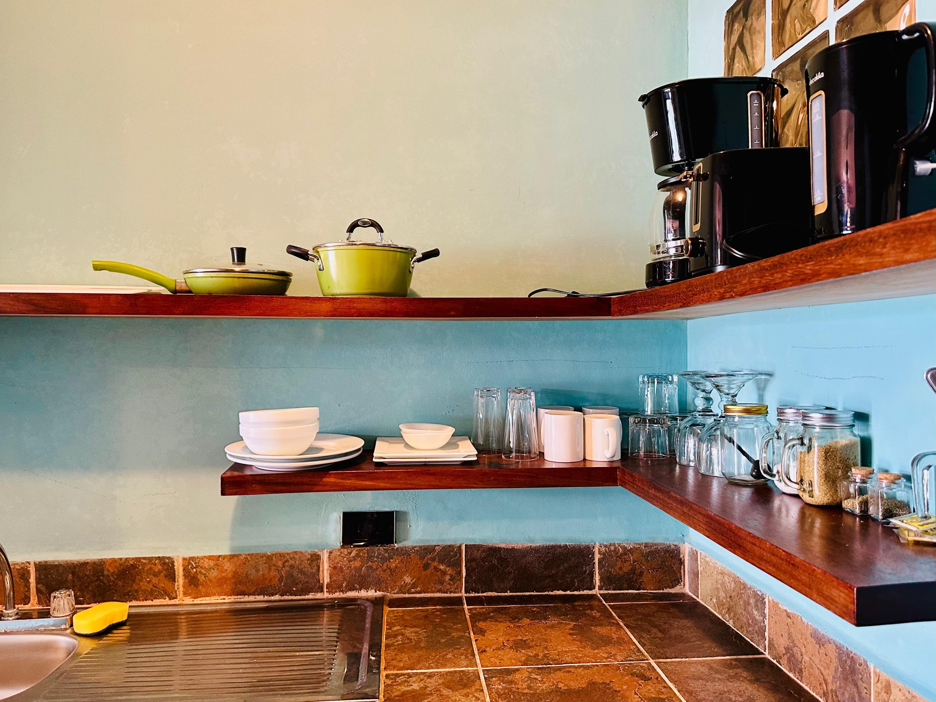 A kitchen with a sink, a yellow sponge, and various kitchen items on shelves.