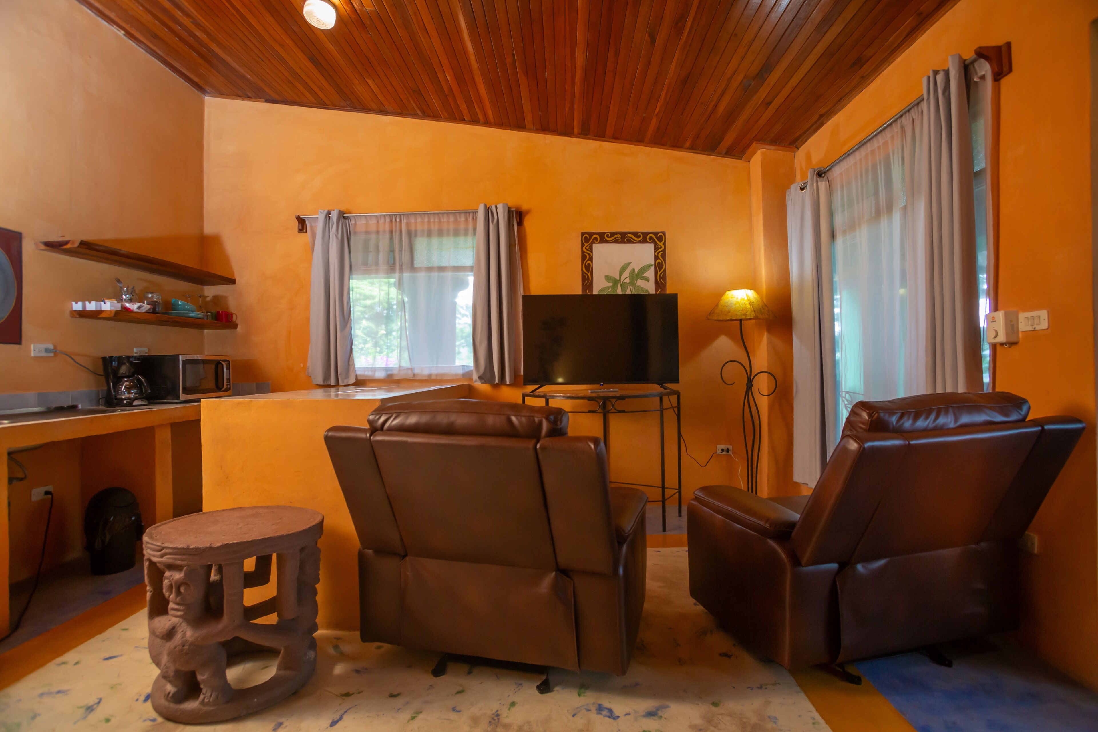 Una sala de estar acogedora con techo de madera, un televisor de pantalla plana, un sofá y un sillón de masaje.