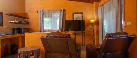 Una sala de estar acogedora con techo de madera, un televisor de pantalla plana, un sofá y un sillón de masaje.