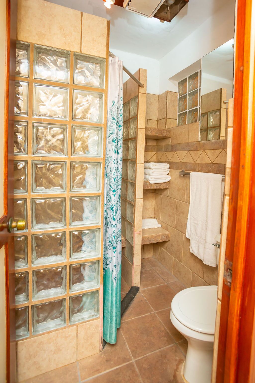 Een badkamer met een glazen deur, een douche en een toilet.