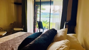 A hotel room with a bed, a chair, and a view of greenery outside. - Lake Arenal Hotel, Brewery & Farm (Santa Rosa)
