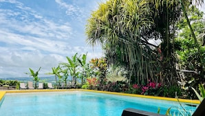 A pool with clear blue water, surrounded by lush greenery and a few lounge chairs. - Lake Arenal Hotel, Brewery & Farm (Santa Rosa)