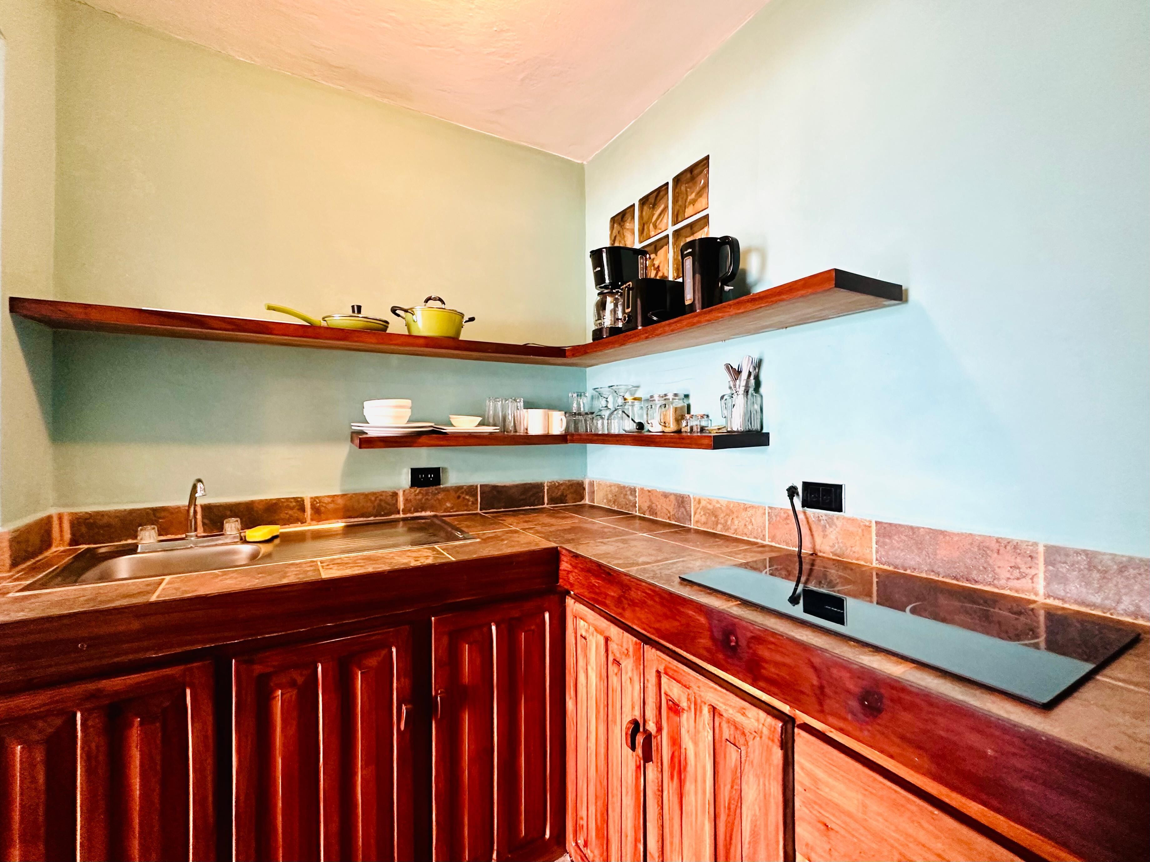 A kitchen with wooden cabinets, a sink, and two wooden shelves above it.