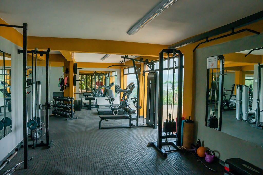 A gym with various exercise equipment, mirrors, and a view of the outdoors.