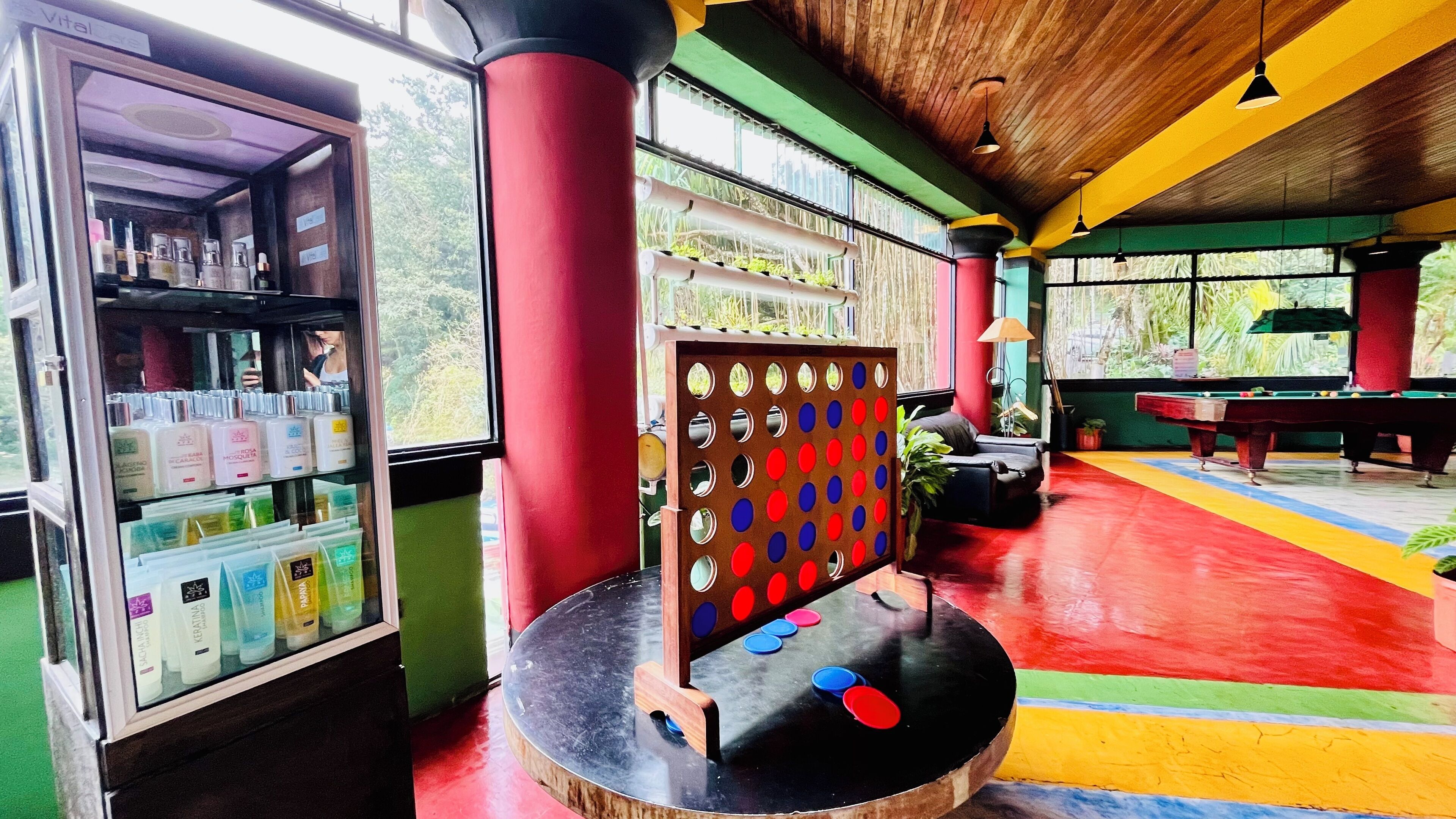A brightly colored indoor space with a pool table, a vending machine, and a pinball machine.