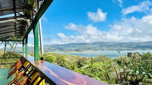 A wooden deck with a view of a lake and hills. - Lake Arenal Hotel, Brewery & Farm (Santa Rosa)