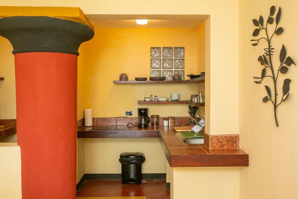 A compact kitchen with a wooden countertop, a coffee machine, and a small sink.