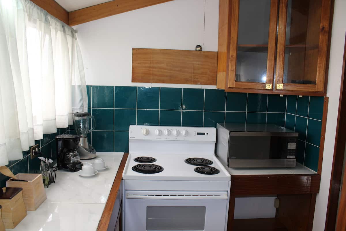 Een keuken met een fornuis, magnetron en houten kasten.