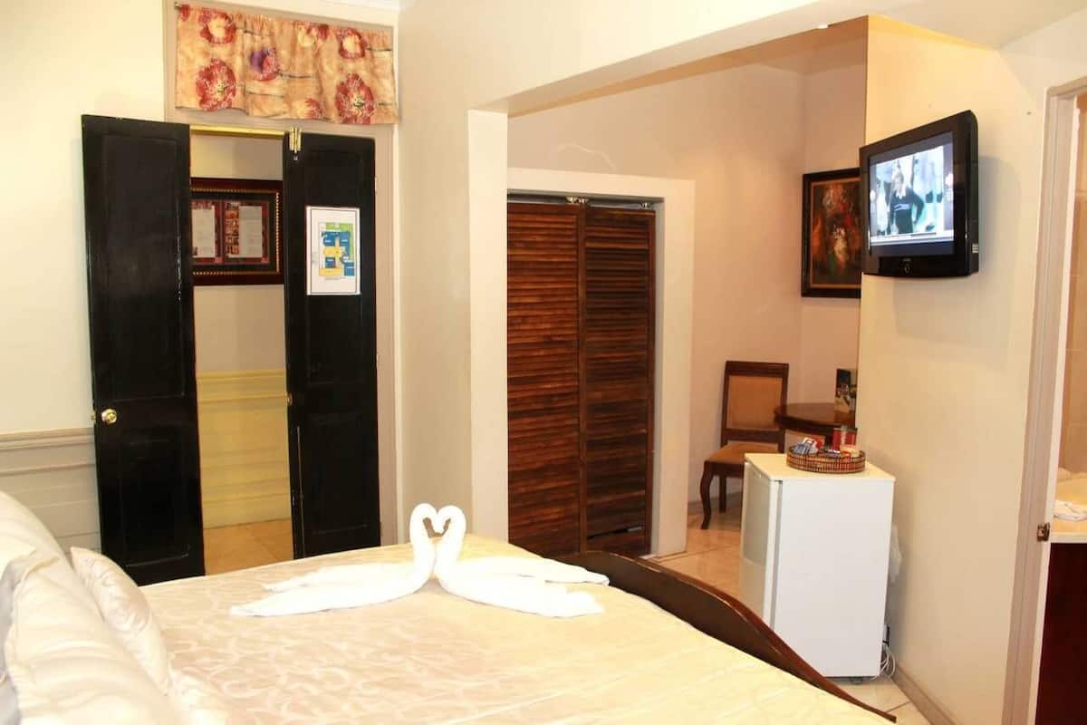 Een hotelkamer met een bed, een televisie, een bureau en een kledingkast.