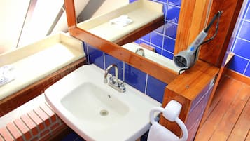A bathroom with a white sink, a mirror, a towel rack, and a hairdryer.